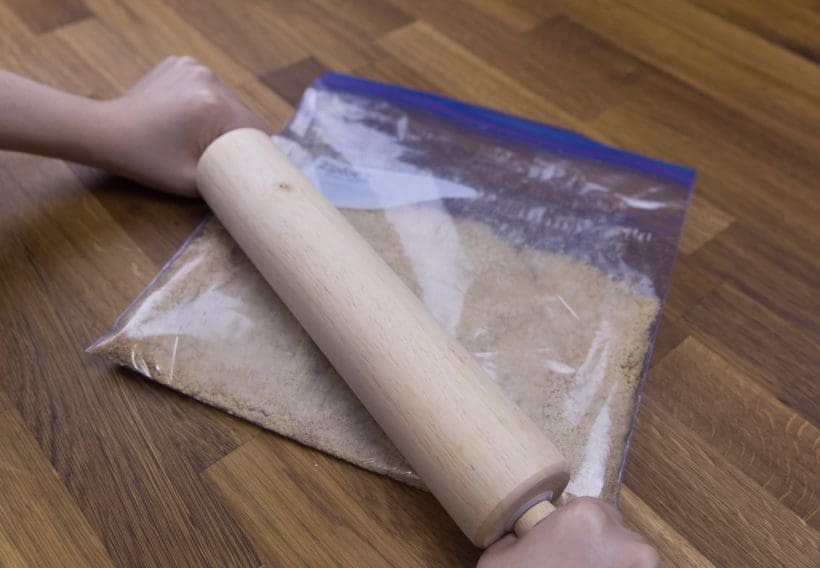 Finely ground graham crackers with rolling pin to create cheesecake crust